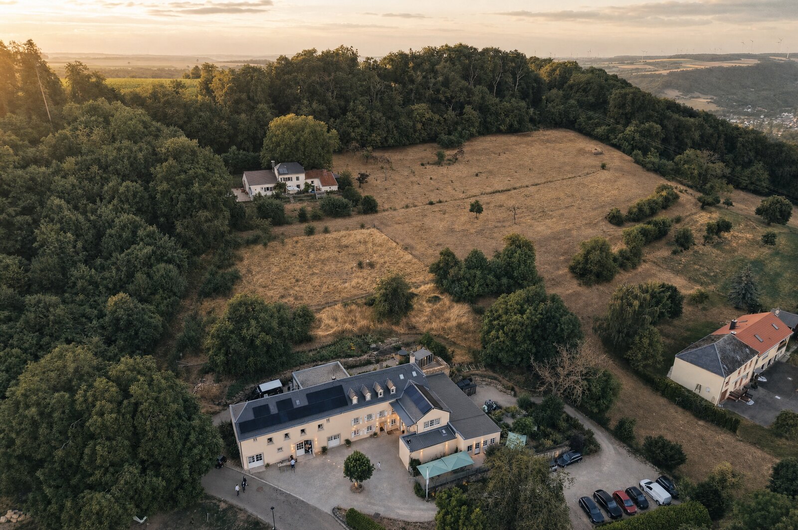 Hazelnut House above the Mullerthal valley from the air — our drone frame of the wedding day in July 2026, stylised