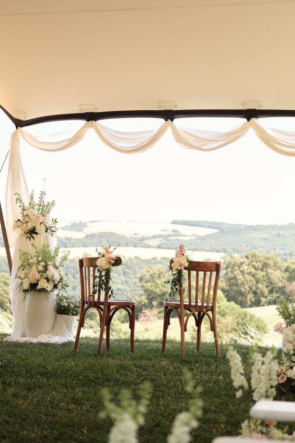 Two chairs and flowers under the ceremony canopy at Hazelnut House, the valley beyond