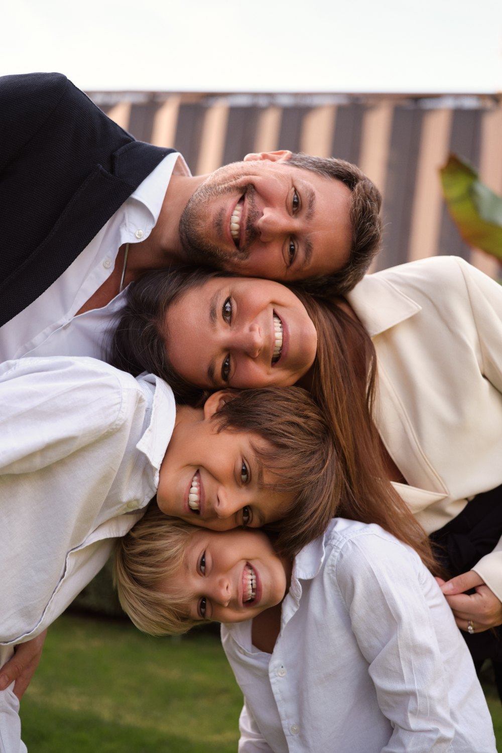 A family of four pressing their cheeks together and laughing at the camera